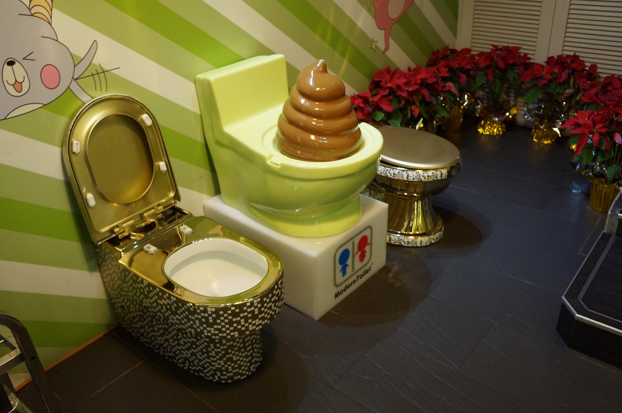 Three fake toilets at Modern Toilet, two gold, one with a big brown poo